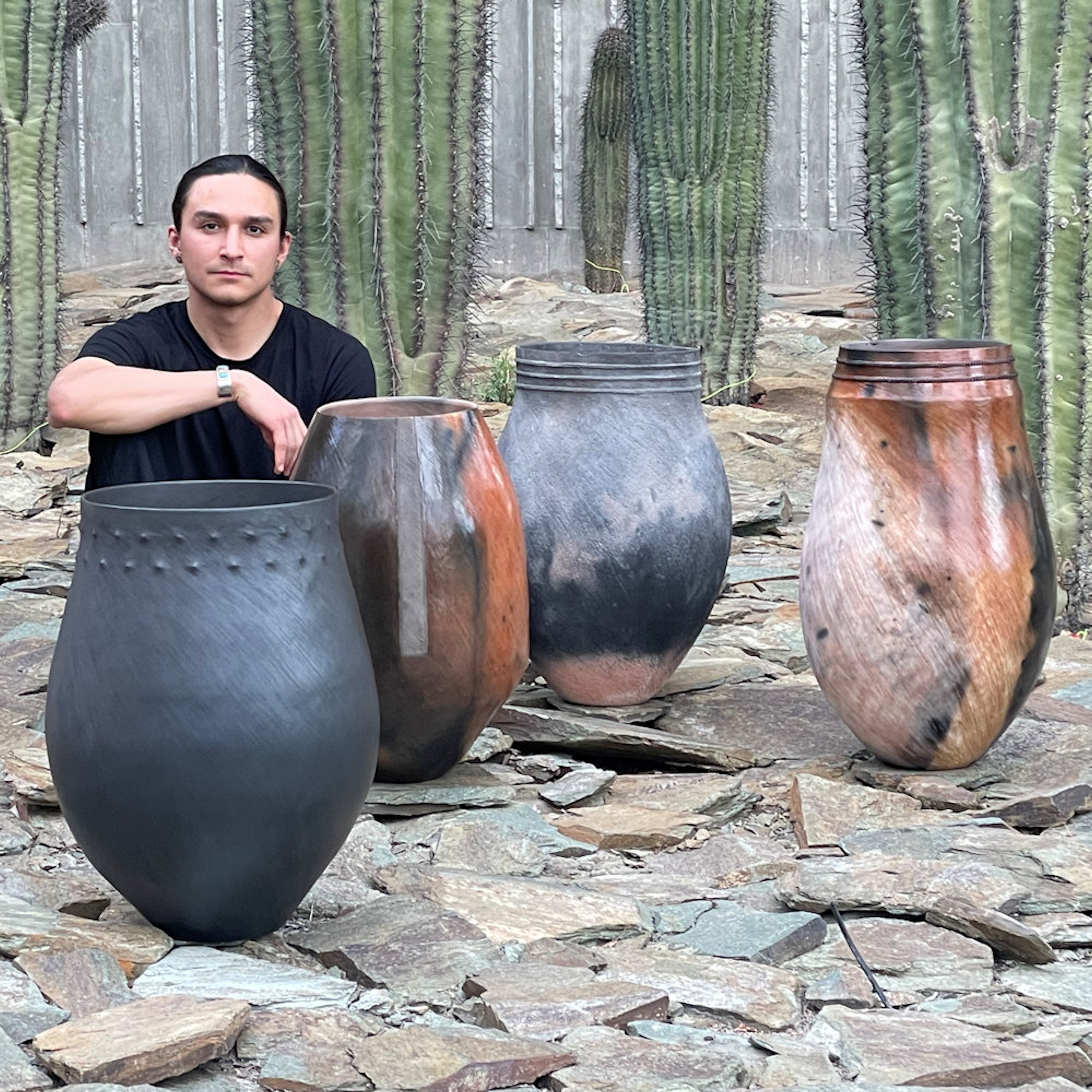 Jared Tso with ceramic pots in front of saguaro cactuses 